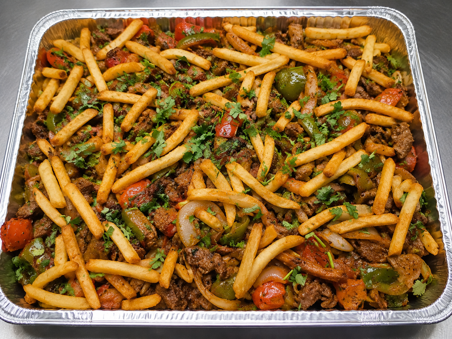 Catering tray with fries, beef, peppers, and herbs